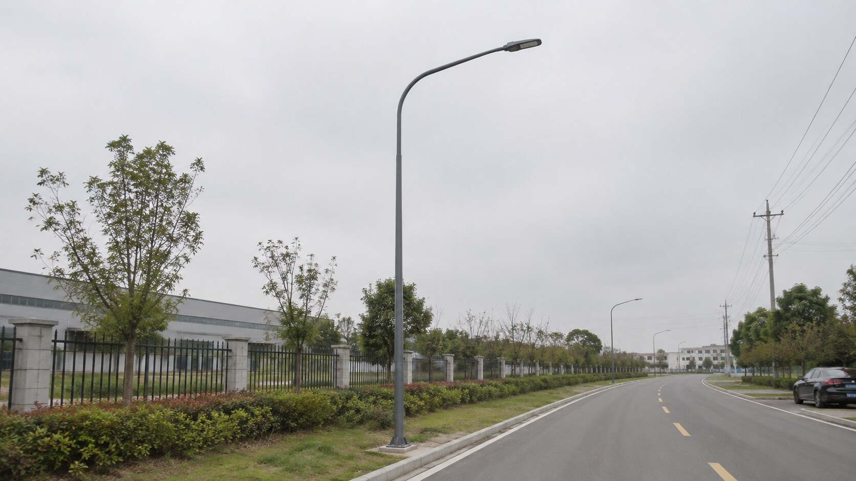 Full-height 6m galvanized curved-arm street light pole beside a local road